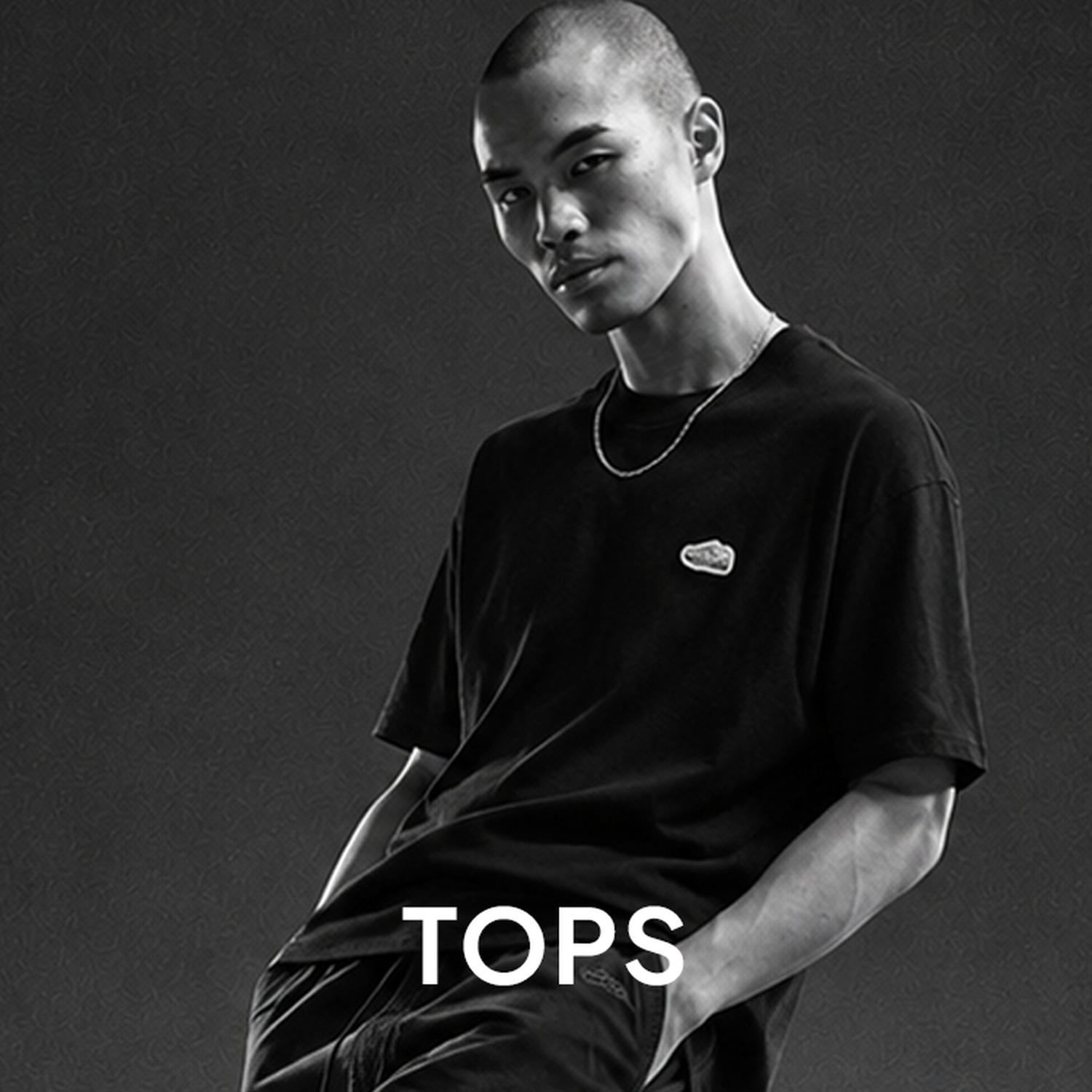 Black-and-white promo image of a male model in a black oversized T-shirt, with the word “TOPS” across the bottom.