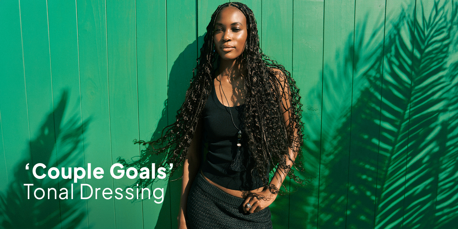 Fashion campaign banner of a woman with long braids in a black sleeveless top and textured skirt posing against a bright green wall, with palm leaf shadows and the text “Couple Goals” and “Tonal Dressing." Mens