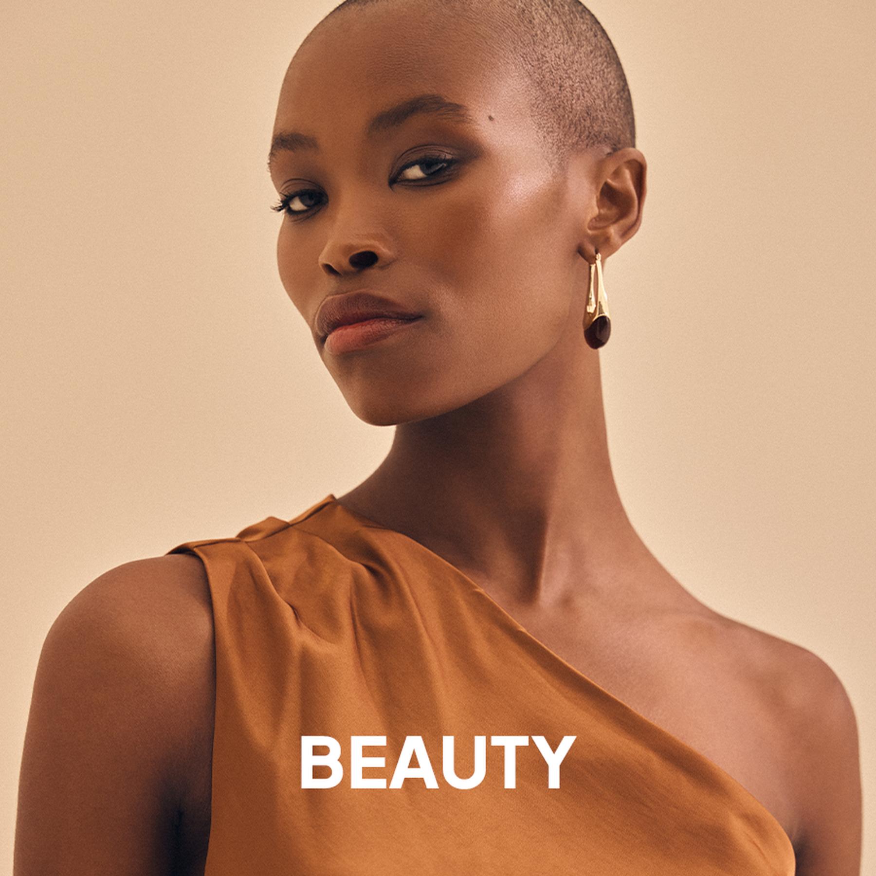 A model wearing a deep red pleated halter neck dress and large silver statement earrings. Beauty and accessories collection.