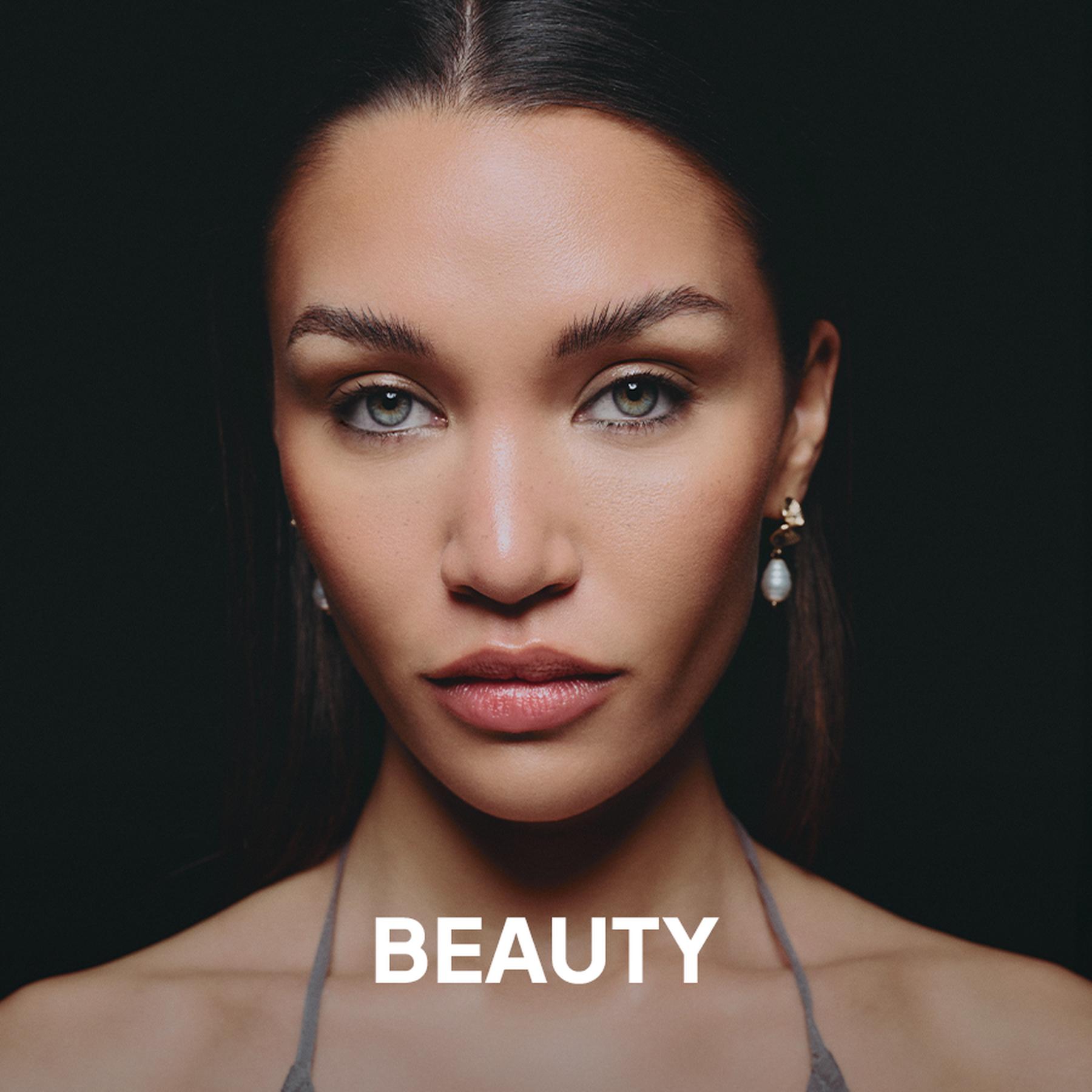 Close-up profile of a Black woman with braided hair wearing large geometric statement earrings against a bright green background, with the word “BEAUTY” overlaid at the bottom.