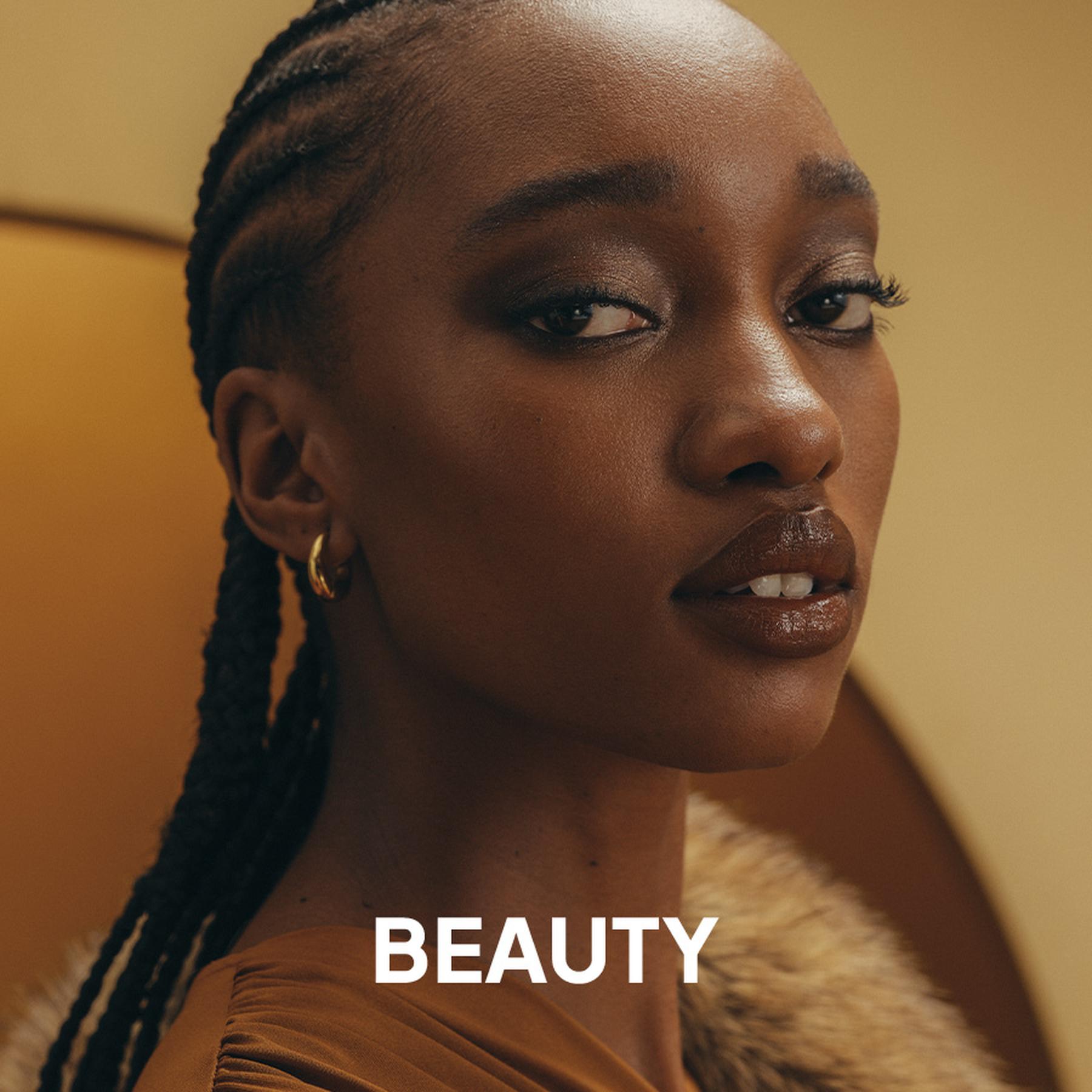 A model wearing a deep red pleated halter neck dress and large silver statement earrings. Beauty and accessories collection.