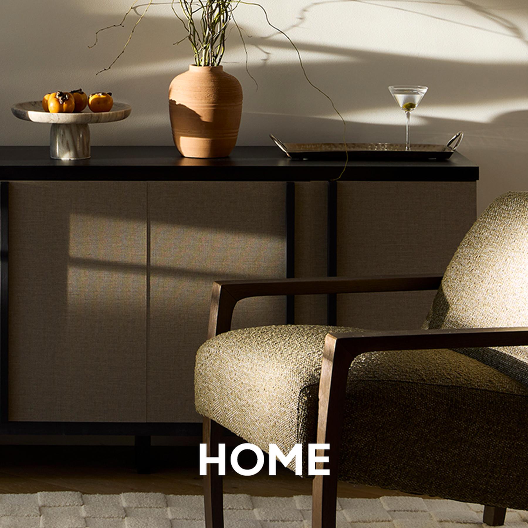 Modern white outdoor armchairs and sculptural side tables are arranged on a dark wood deck. Home and patio collection.