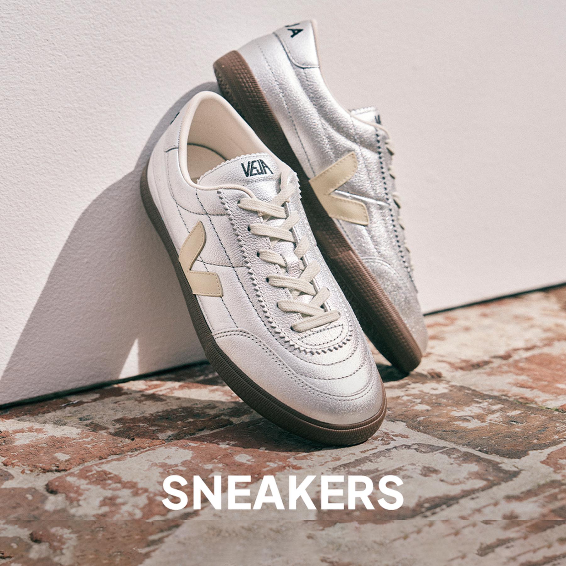 Close-up of cream sneakers with brown stripes paired with white ruffled socks and a lace skirt. Sneakers collection.