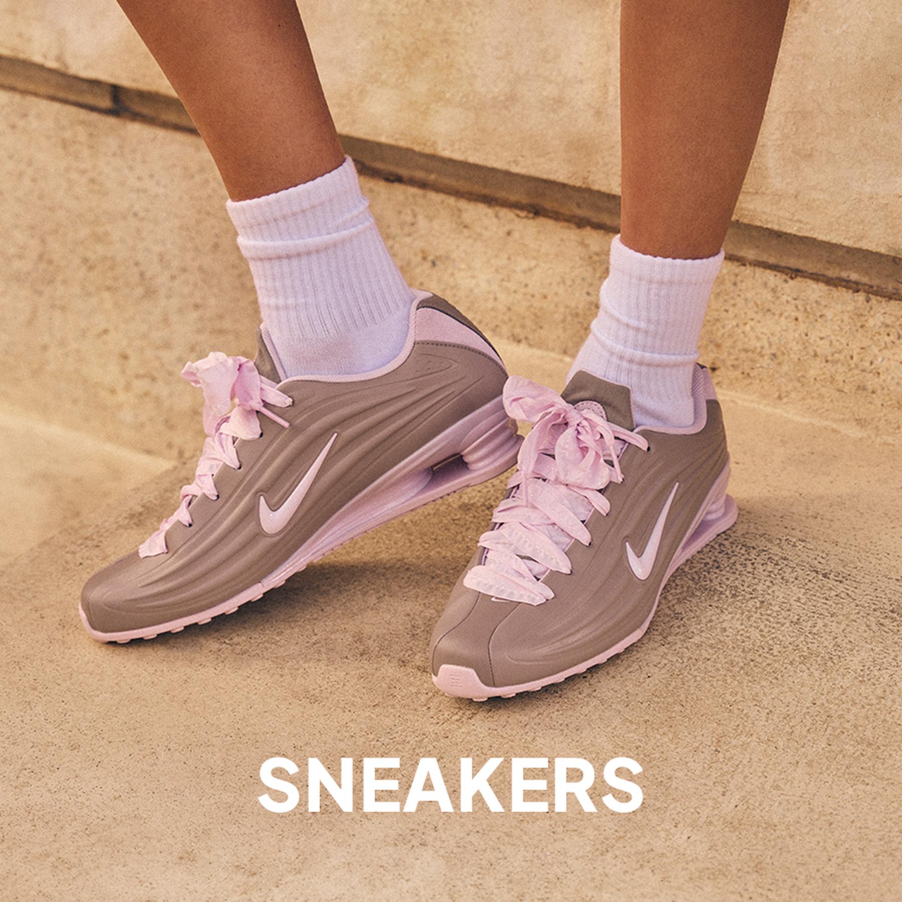 Close-up of cream sneakers with brown stripes paired with white ruffled socks and a lace skirt. Sneakers collection.