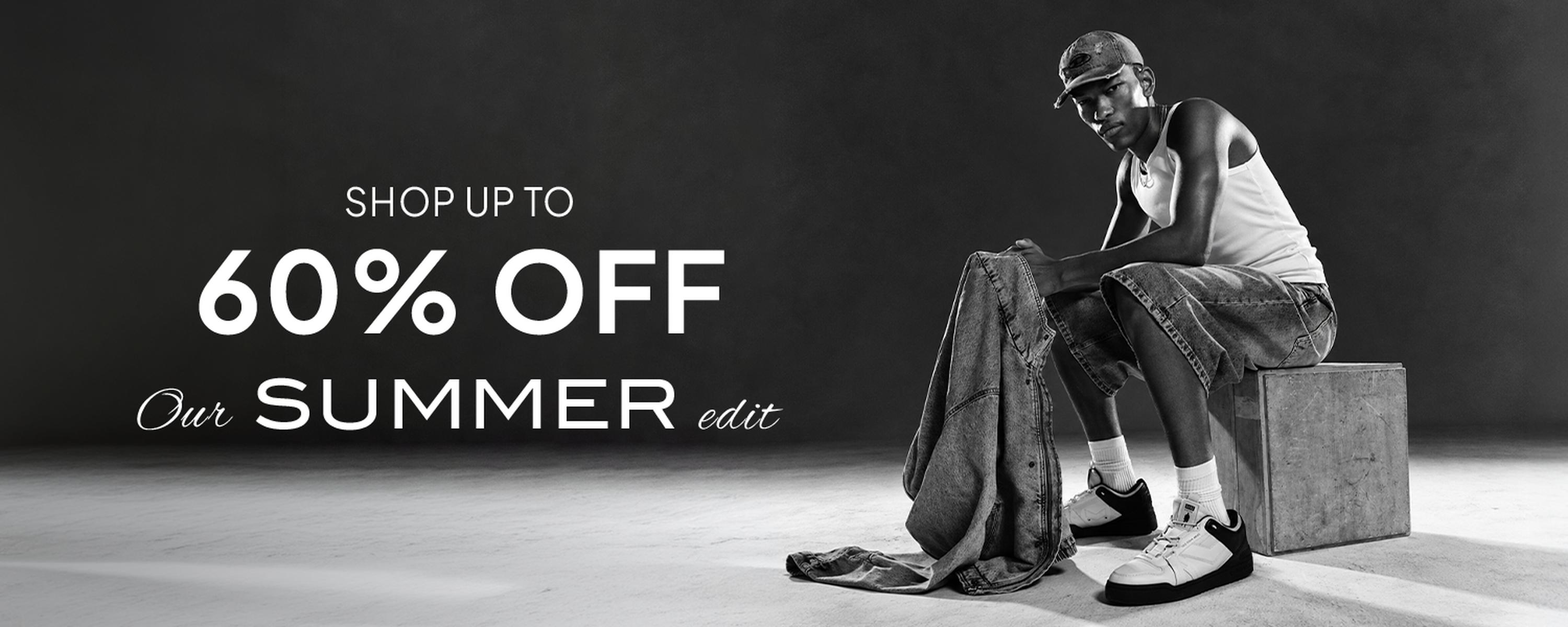 Black-and-white men’s fashion promo featuring a male model in a cap, tank top, and cropped jeans sitting on a block beside folded clothing, with bold text reading “SHOP UP TO 60% OFF Our SUMMER edit.”