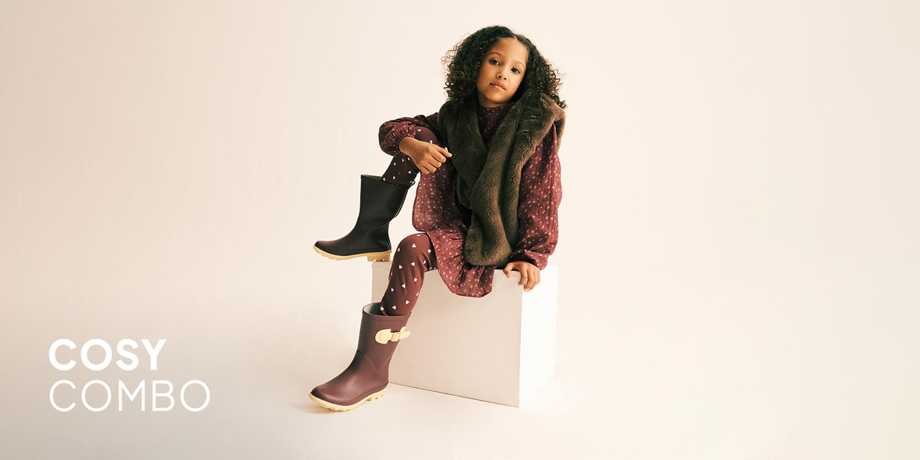 Kids' Warm Hues fashion campaign showcases a burgundy corduroy dress, a floral long-sleeve top, and white Mary Jane shoes.