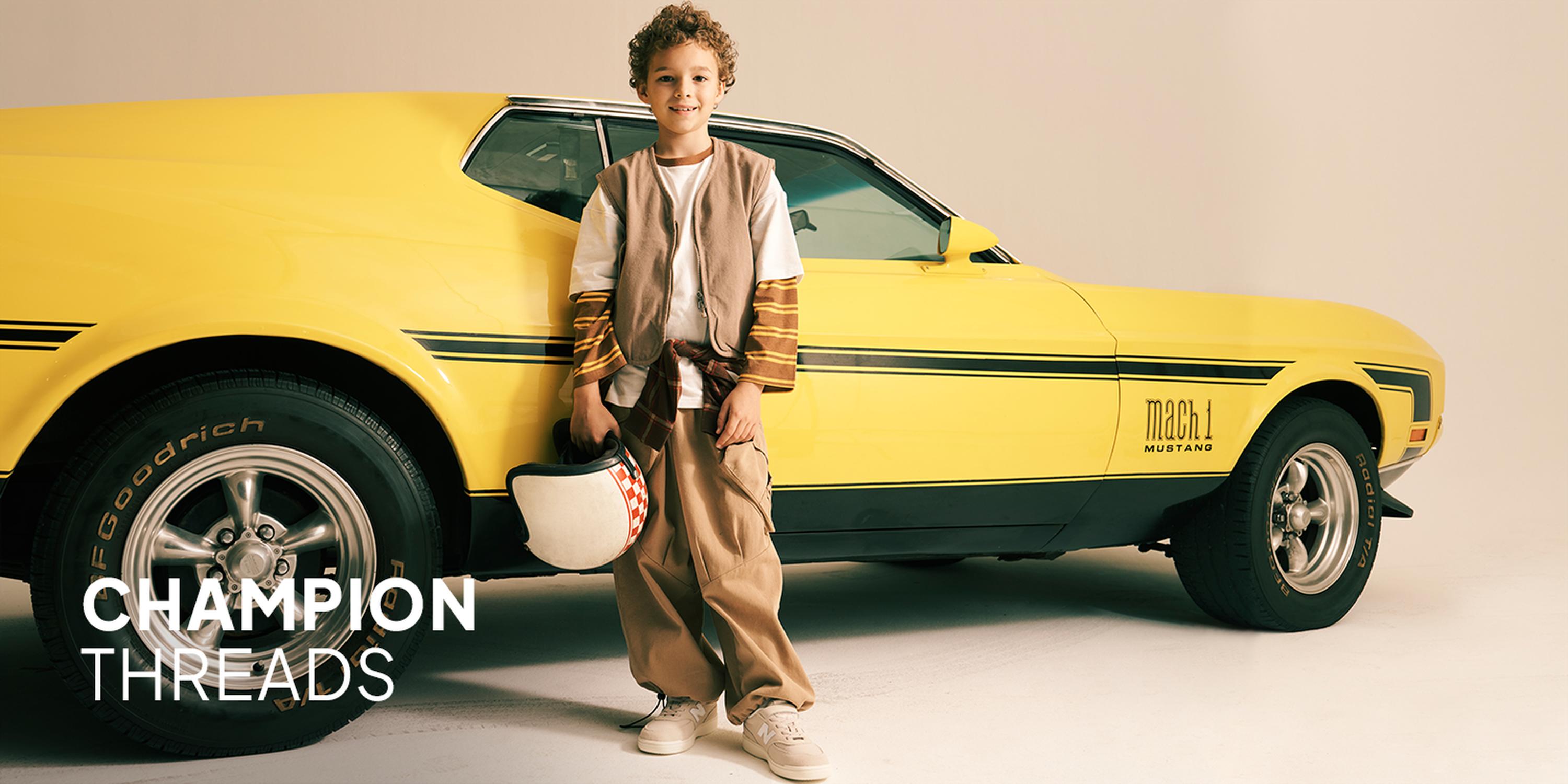 Kids' Woven In fashion collection: Boy wearing a blue puffer vest over a cream striped knit sweater, khaki joggers, and tan lace-up boots.