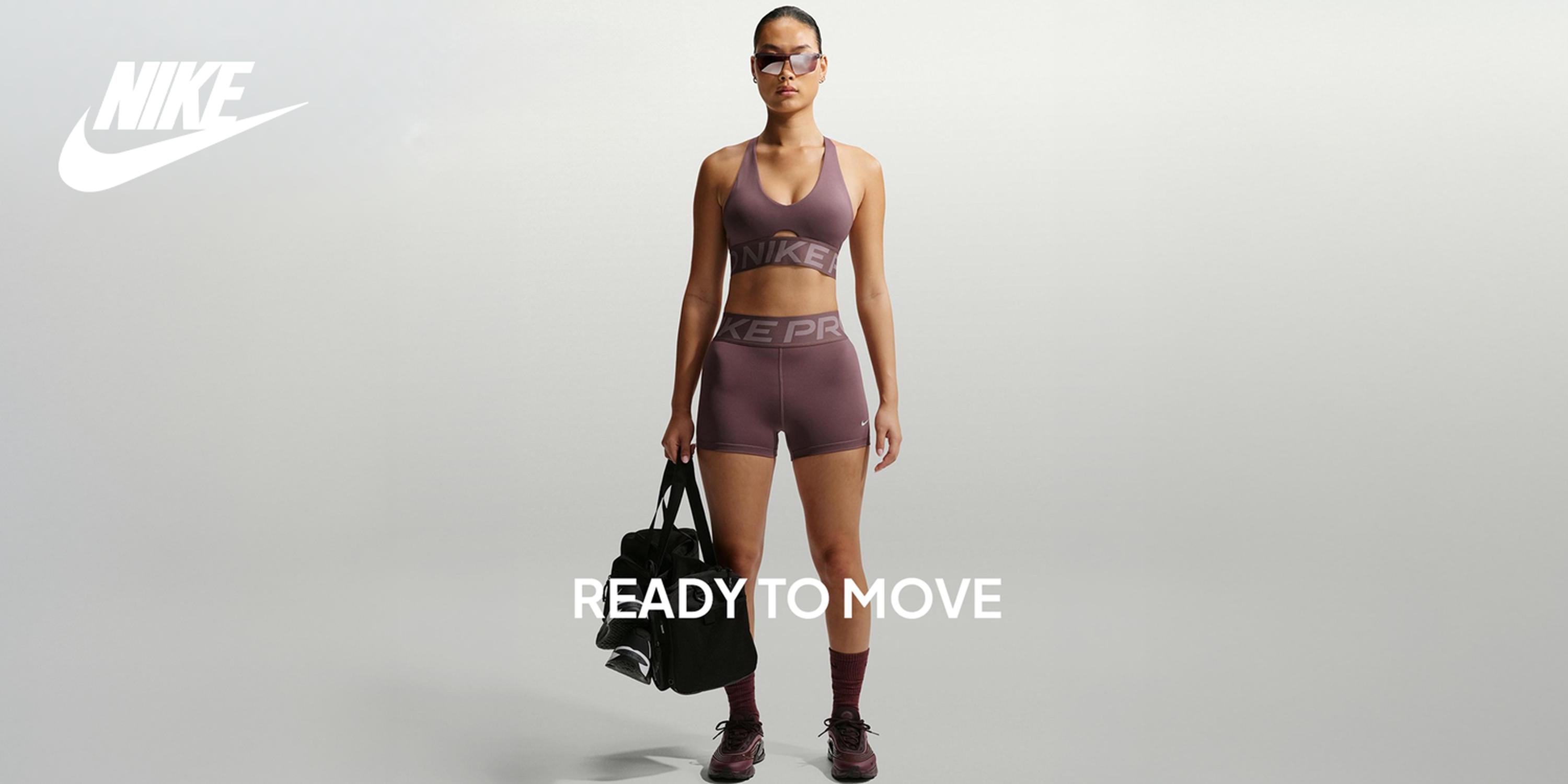 Nike hero banner featuring a woman in purple Nike Pro workout set holding a gym bag, with the Nike logo and “READY TO MOVE” text on a light grey background.
