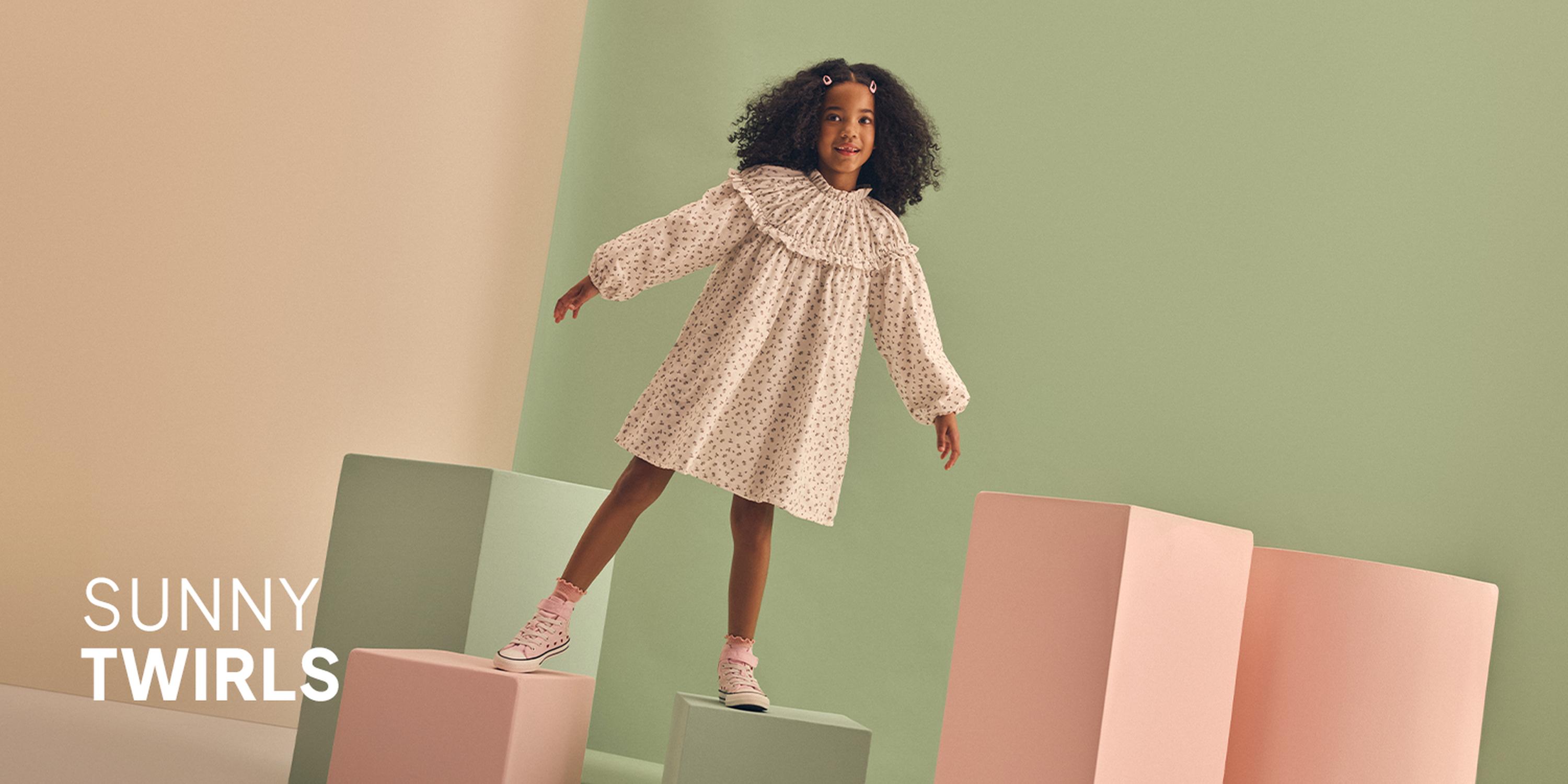 Kids' Warm Hues fashion campaign showcases a burgundy corduroy dress, a floral long-sleeve top, and white Mary Jane shoes.