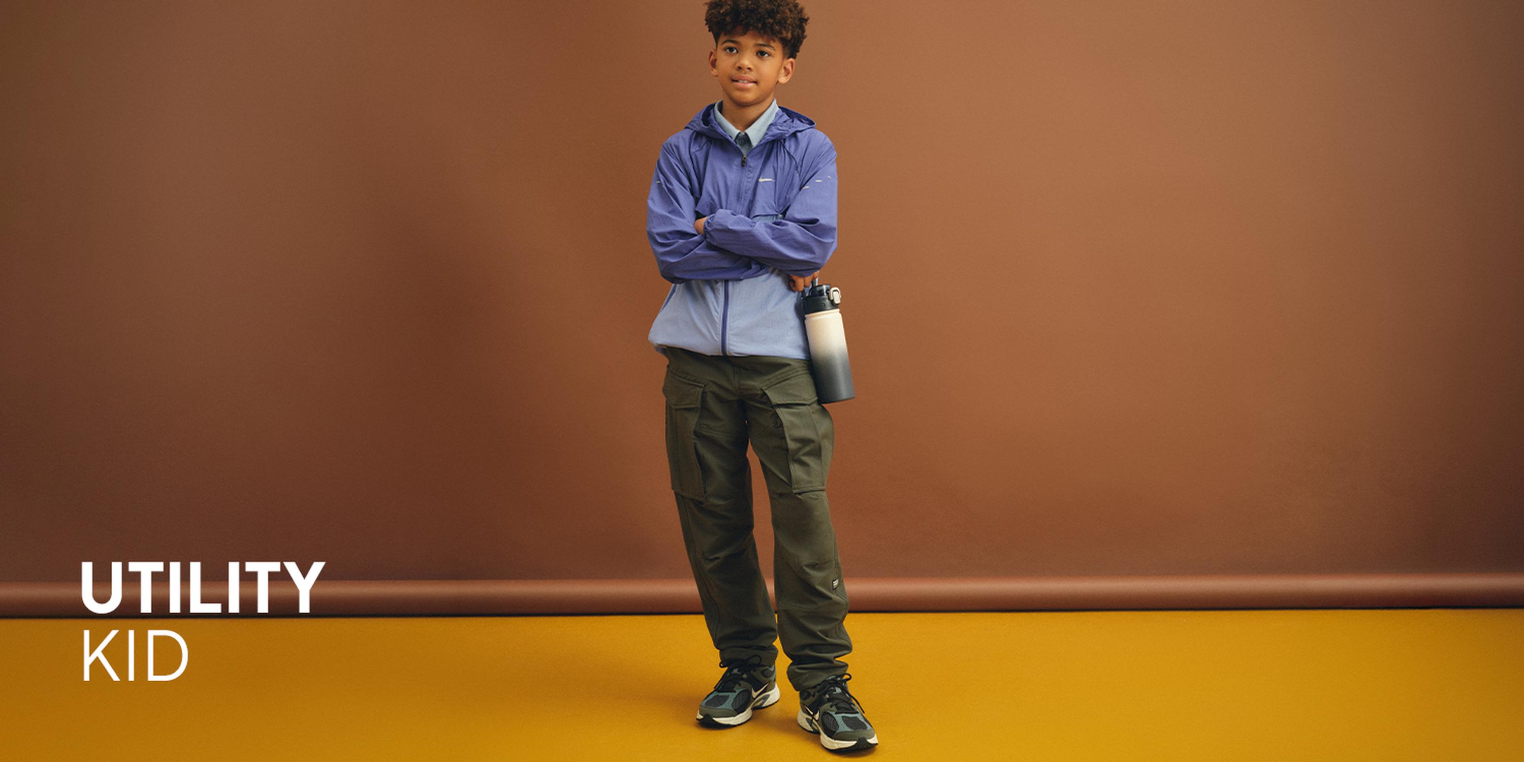 Kids' Let's Play sportswear campaign: Boy modeling a grey Nike logo sweatshirt, matching shorts, and white triple-strap sneakers.