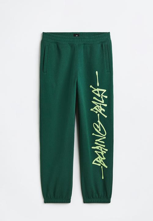 H&M - Loose fit printed sweatpants - dark green/boring pals