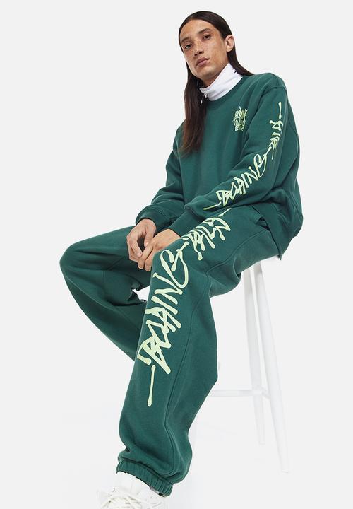 H&M - Loose fit printed sweatpants - dark green/boring pals