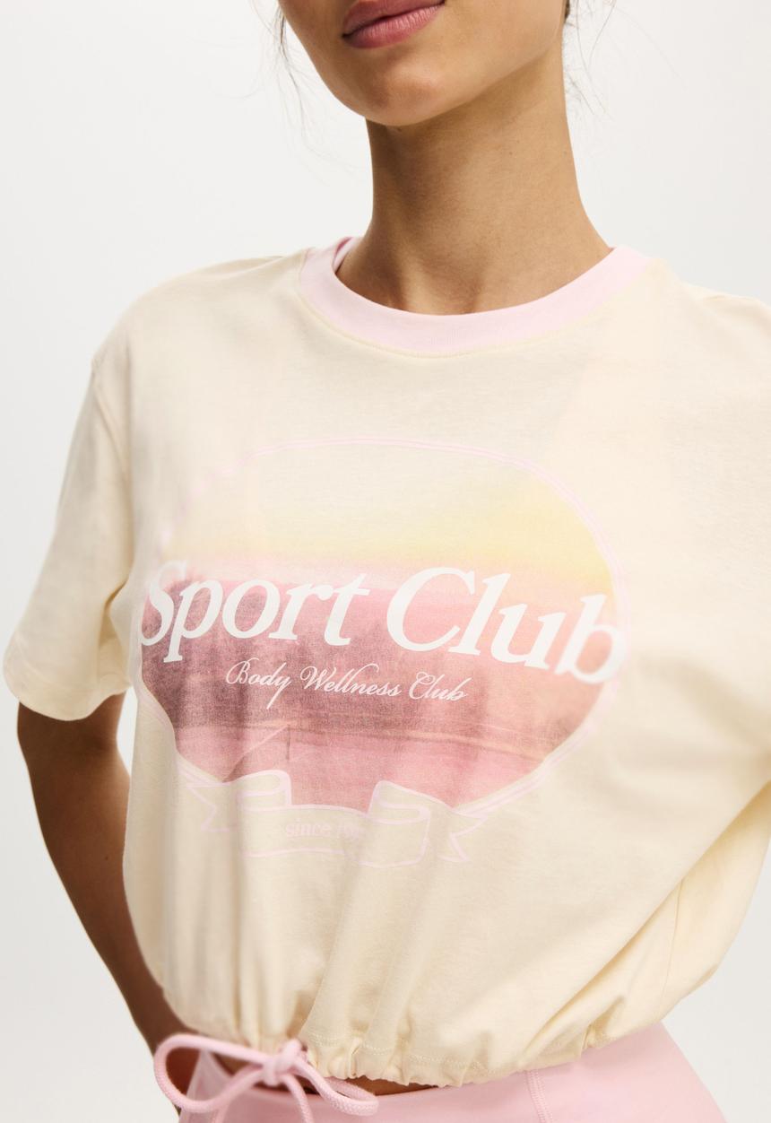 Cotton On - Active Graphic Tie Up Tee - Coconut Milk/Sport Club