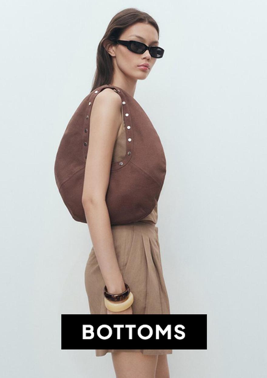 Woman wearing wide-leg cream denim culottes with a cropped, wide-fit silhouette, paired with a burgundy strappy top and black sandals, featured as part of the Black Friday Bottoms deals at SUPERBALIST