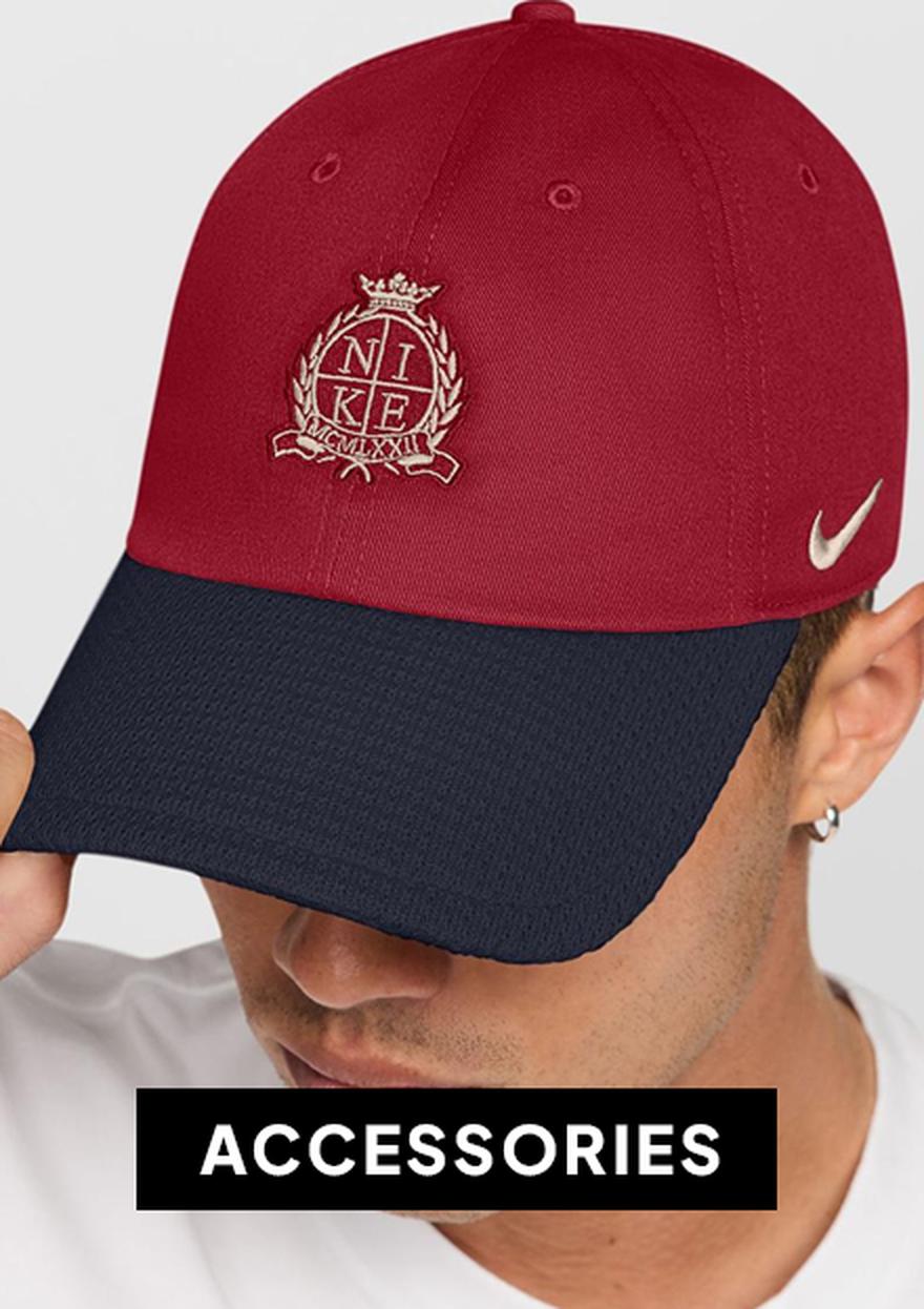 Black Nike cap accessories banner showing a man wearing a red and navy Nike hat on a white background, with bold “ACCESSORIES” text below.