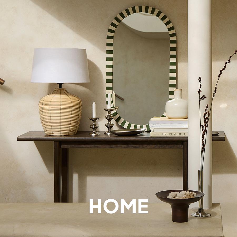 Modern white outdoor armchairs and sculptural side tables are arranged on a dark wood deck. Home and patio collection.