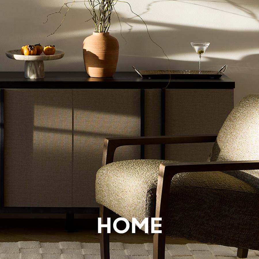 Modern white outdoor armchairs and sculptural side tables are arranged on a dark wood deck. Home and patio collection.