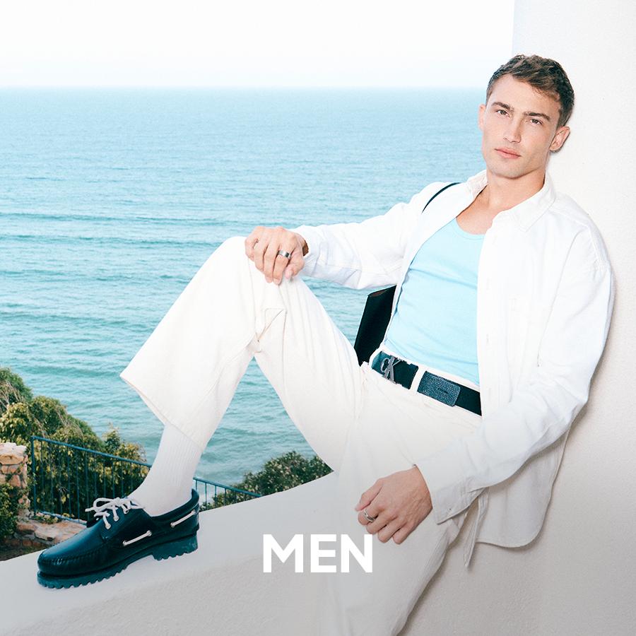 Male model in a leather biker jacket and relaxed-fit pants with sunglasses, showcasing modern men's fashion. Men's apparel.