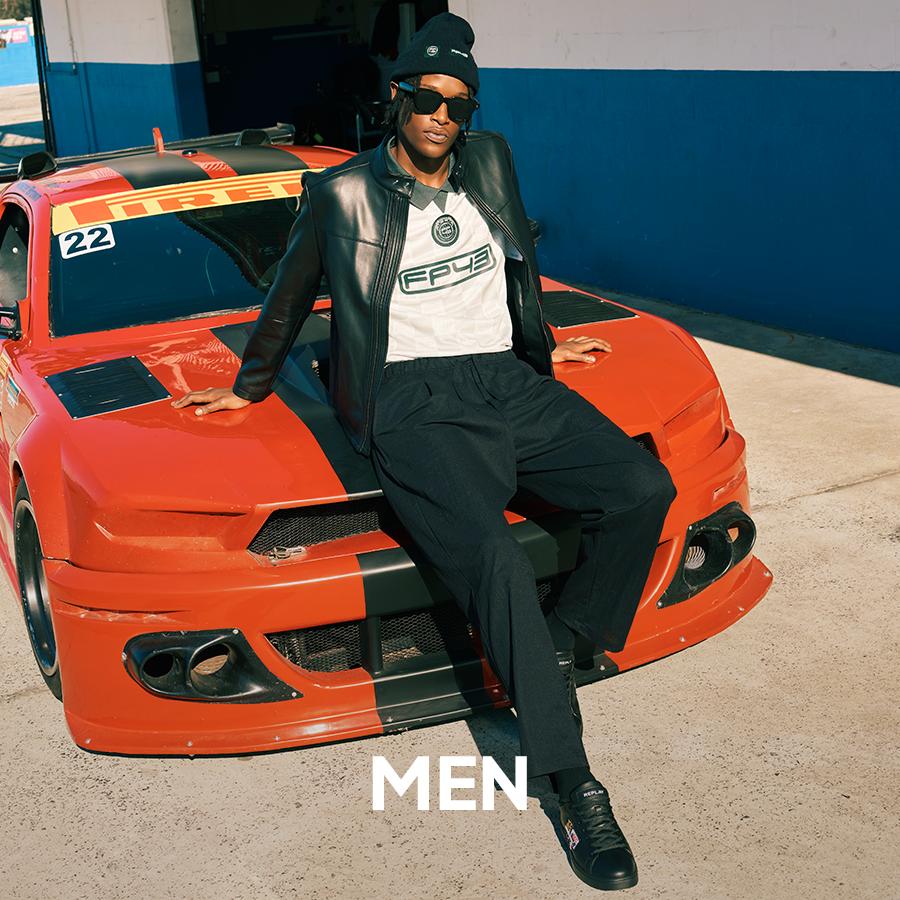 Male model in a leather biker jacket and relaxed-fit pants with sunglasses, showcasing modern men's fashion. Men's apparel.