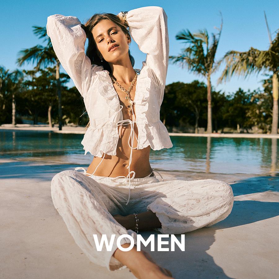 Superbalist women’s fashion banner showing a model in a flowing white outfit reclining by a pool, with “WOMEN” text overlaid.
