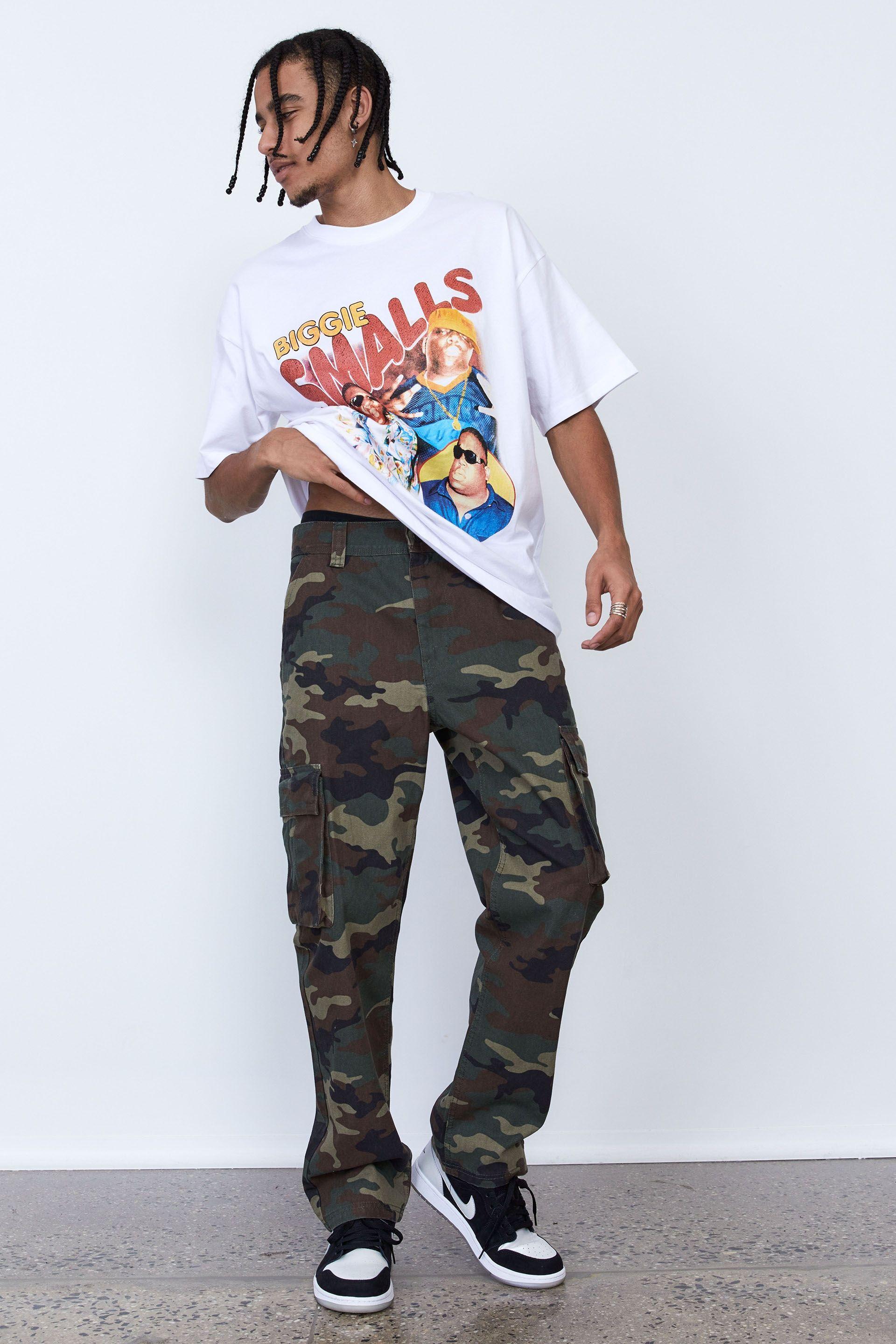Full streetwear outfit with a white oversized graphic T-shirt, straight camouflage cargo pants and black-and-white sneakers